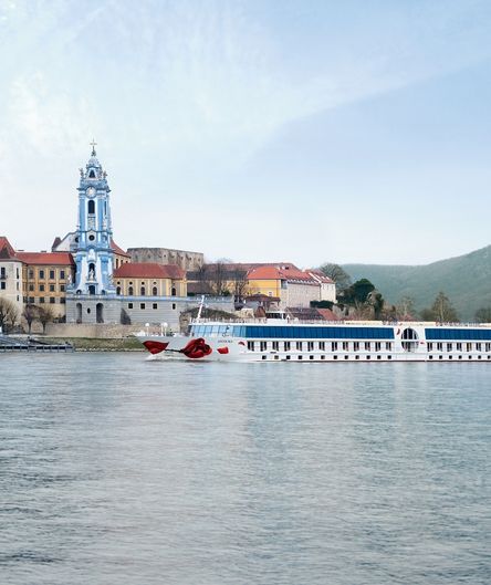 Ein Flusskreuzfahrtschiff der A-ROSA-Flotte passiert die Ortschaft Dürnstein in der Wachau mit dem blau-weißen Turm des Stiftes Dürnstein im Hintergrund. Ein Flusskreuzfahrtschiff der A-ROSA-Flotte passiert die Ortschaft Dürnstein in der Wachau mit dem blau-weißen Turm des Stiftes Dürnstein im Hintergrund.